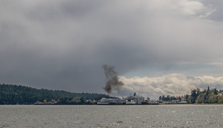 Apr 18, 2023 - Nanaimo, Canada: A puff of black smoke exits the exhaust pipe of a large BC Ferries ship docked at Departure Bayのeditorial素材