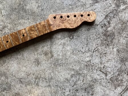 Bird eye maple guitar neck on old grey concrete with space. concept for wallpaper and writing textの写真素材
