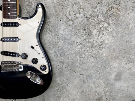 vintage black electric guitar on grey concrete with space. concept for wallpaper and writing textの写真素材