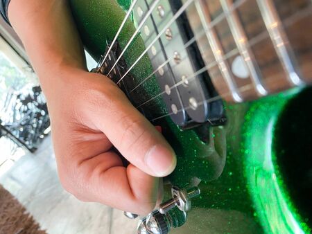 close up shot of guitarist hands playing sparkle green guitar with focus on handsの写真素材