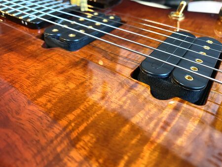 Closeup nickel stings and black pickup the orange guitar patterned wood Koa.の写真素材