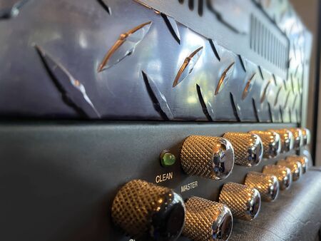 Close-up vintage head power amplifier with silver knob and black control panel. clean and hi-gain distortion for rock to metal, Blues, and jazz genres. Music business concept.の写真素材