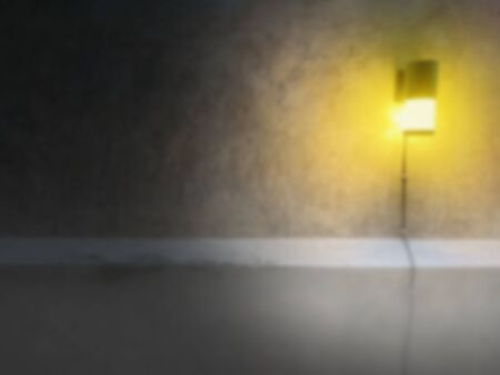 The blurred octagonal lamp that gives a warm yellow glow is attached to the broken concrete wall. And there is a little fog at the bottom.There is a copy space on the left. The concept of loneliness.の写真素材