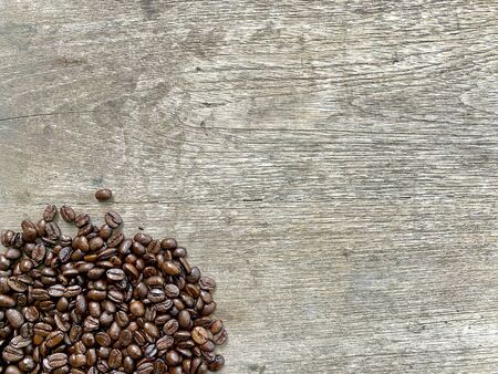 arabica coffee beans placed on the brown wooden tables in a mock-up style have a fresh, delicious aroma. It's an idea for making a menu plan with copy space. wallpaper, background and backdrop.の写真素材