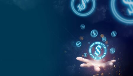 The hand of a person holding a silver coin symbol That is emitting blue light Seems like the power to make money. Ideas for businesses that make money Or the money that is floating away in the sky.の写真素材