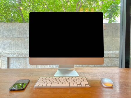 Selective focus Computer monitor With keyboard and mouse With a black smartphone Resting on wooden...
