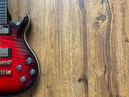 red burst electric guitar made from a genuine alder wood Popular musician on veneer brown wood background with copy space on right for letter. business and music concept. Wallpaper or background.の写真素材
