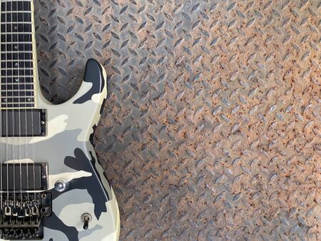 grey camo electric guitar made from a genuine mahogany wood Popular musician on veneer brown steel background with copy space on right for letter. business and music concept. Wallpaper or background.の写真素材