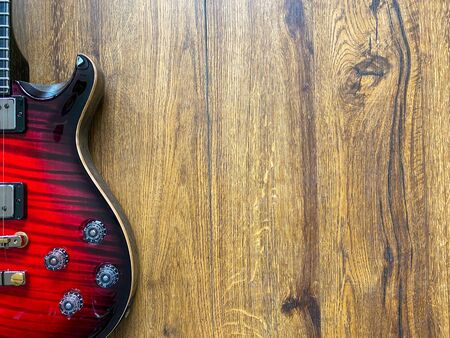 red burst electric guitar made from a genuine alder wood Popular musician on veneer brown wood background with copy space on right for letter. business and music concept. Wallpaper or background.の写真素材