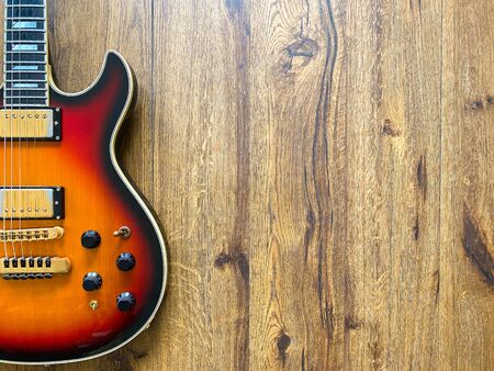 sunburst electric guitar made from a genuine alder wood Popular musician on veneer brown wood background with copy space on right for letter. business and music concept. Wallpaper or background.の写真素材