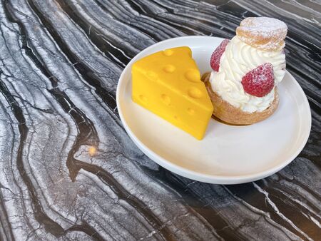 The cake that looks like deliciously delicious yellow cheese cubes, bread topping with whipped cream, and the strawberry is placed on a black-gray marble table with copy space.の写真素材