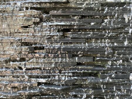 Black gray brickblock wall With water flowing like a waterfall, giving a fresh feeling Like nature There is a soft light entering the right hand side. background, wallpaper and backdrop.の写真素材
