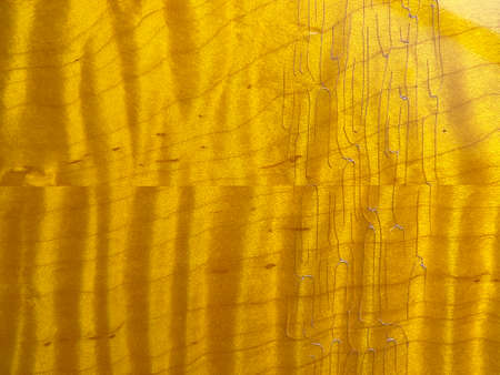 Abstract genuine flame maple wood dyed is yellow lemon burst and  high gloss lacquered with cracks background, backdrop and texture with copy space. top view.の写真素材