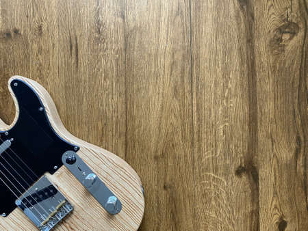 natural electric guitar made from a genuine Ashwood Popular musician on veneer brown wood background with copy space on right for letter. business and music concept. Wallpaper or background. top view.の写真素材