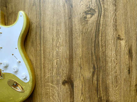 24k gold electric guitar made from a genuine alder Popular musician on veneer brown wood background with copy space on right for letter. business and music concept. Wallpaper or background. top view.の写真素材