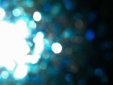 Abstract blue glitter bokeh Looks like a firework effect texture on black background. glitter vintage lights defocused elegant for cosmetics or celebrate. Sparkling magical dust particles.の写真素材