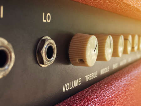 Close-up vintage cream volume knob of the boutique clean guitar amplifier with blurred brown control panel and red leather cover. classic vintage style filter. Music business concept.の写真素材