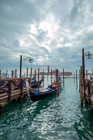 Photograph of Gondola's docked on the shore of Venice, Italy. Cloudy overcast day, surrounded by water.の写真素材