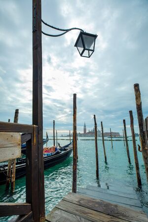 Photograph of Gondola's docked on the shore of Venice, Italy. Cloudy overcast day, surrounded by water.の写真素材