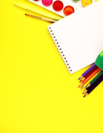School stationery on a yellow background, top view. paint, Notepad, and colored pencilsの写真素材