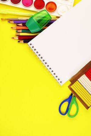 School stationery on a yellow background, top view. paint, Notepad, and colored pencilsの写真素材