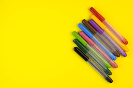 markers of different colors on a yellow background, top view. close-up markers are laid out in a rowの写真素材