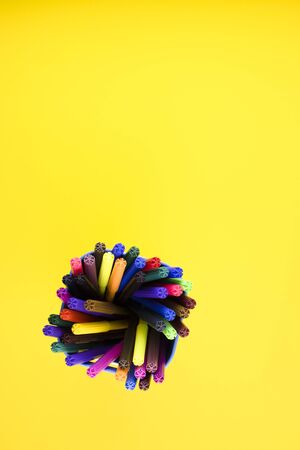rainbow markers isolated on a yellow background top view. multicolored pens gathered together close upの写真素材