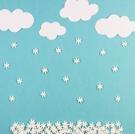 white paper snowflakes fall from clouds on a blue background. winter holiday background for Christmas and New yearの写真素材