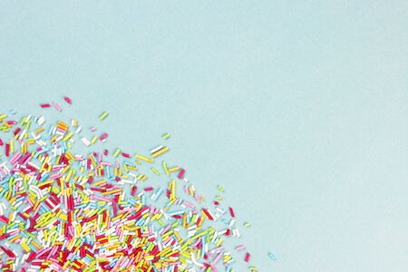 culinary pastry rainbow sprinkles are scattered on a blue background. small sugar sprinkles for decorating cakesの写真素材