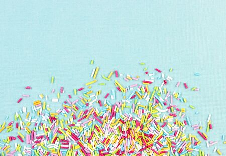 culinary pastry rainbow sprinkles are scattered on a blue background. small sugar sprinkles for decorating cakesの写真素材