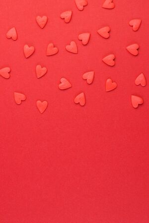 background for Valentine's day, small red paper hearts. The symbol of love is strewn on a red background top viewの写真素材