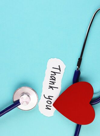 medical stethoscope, red healthy heart and thank you doctor text on blue background. concept of gratitude to health workers during a pandemicの写真素材