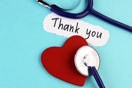 medical stethoscope, healthy red heart and the inscription Thank you on a blue background. concept of gratitude to medical workers during the coronavirus pandemicの写真素材