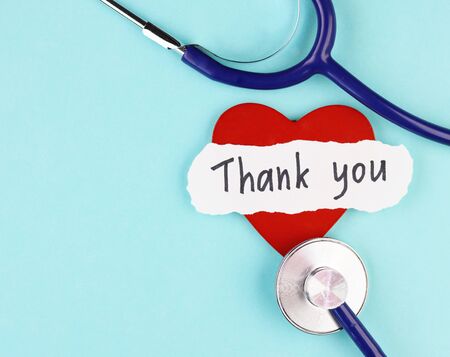 medical stethoscope, healthy red heart and the inscription Thank you on a blue background. concept of gratitude to medical workers during the coronavirus pandemicの写真素材
