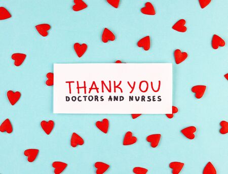 lots of little red hearts and the inscription Thank you to doctors and nurses on a blue background. concept of gratitude to medical workers during the coronavirus pandemicの写真素材