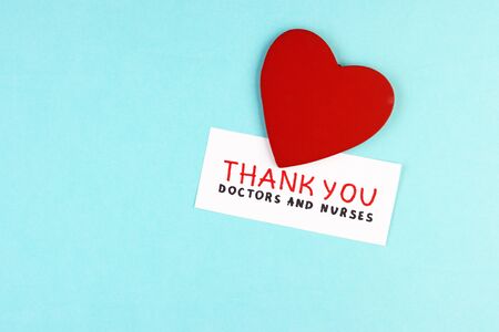 healthy red heart and the inscription Thank you to doctors and nurses on a blue background. concept of gratitude to medical workers during the coronavirus pandemicの写真素材