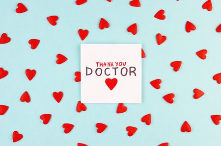 lots of little red hearts and the inscription Thank you to doctor on a blue background. concept of gratitude to medical workers during the coronavirus pandemicの写真素材