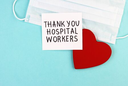 medical mask, healthy red heart and the inscription Thank you to hospital workers on a blue background. concept of gratitude to medical workers during the coronavirus pandemicの写真素材