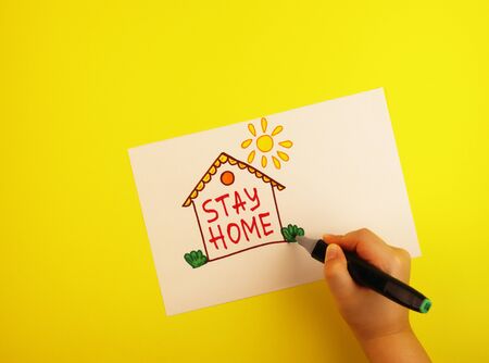 the hand draws a house with the words stay at home. concept of self-isolation during the Covid-19...
