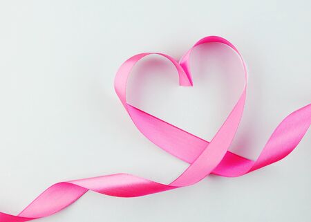 pink heart ribbon isolated on a blue background. silk fabric in the form of a heart. background for Valentine's dayの写真素材