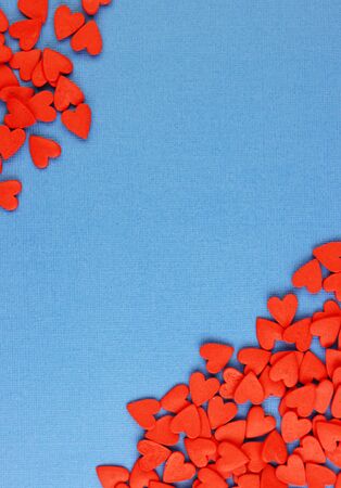 many red hearts are scattered on a blue background, top view. pastel background for Valentine's day and women's holidaysの写真素材