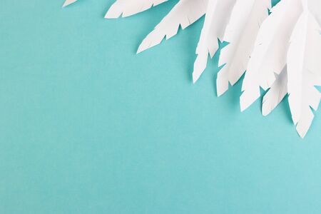 white paper feathers on a blue background, top view. paper decoration on a pastel backgroundの写真素材