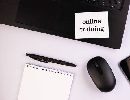 Notepad with a pen and a sheet of text online training. black computer with a notebook on the table...