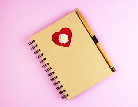 a love heart on a Notepad with a pen on a blue wooden table. brown notebook with a red heartの写真素材