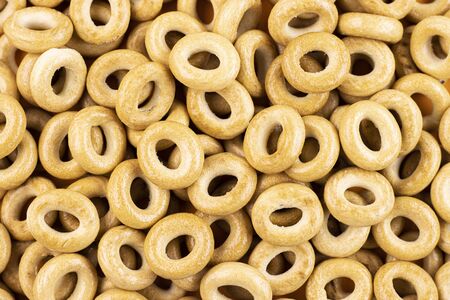 Round bagels close-up on a red background. A pile of scattered bagels. Diet cookies on an orange backgroundの写真素材