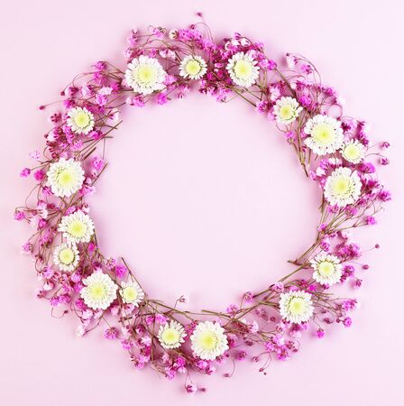 purple flowers on a pink background top view. many spring flowers arranged in a circle. women's wreath of flowersの写真素材