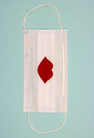medical mask with a red kiss, lips in the center. the concept of restricting kissing and lip-painting for lovers due to quarantine.の写真素材
