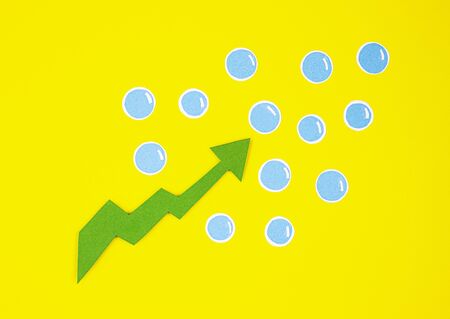 the paper green arrow is pointing upwards with blue bubbles on a yellow background. the concept of increase, growth, success, increase of somethingの写真素材