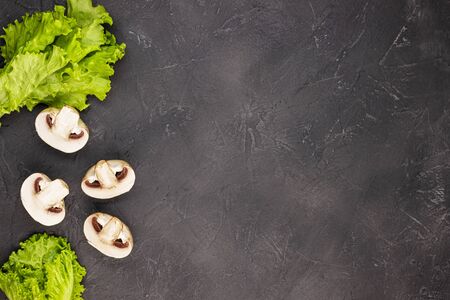 raw mushrooms and fresh greens on a black marble background, top view. The concept of a healthy lifestyle, proper nutritionの写真素材