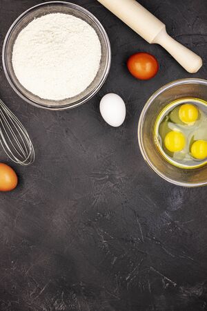 Dark marble baking background with whole and beaten eggs, flour and rolling pin, top view. The concept of a healthy lifestyleの写真素材